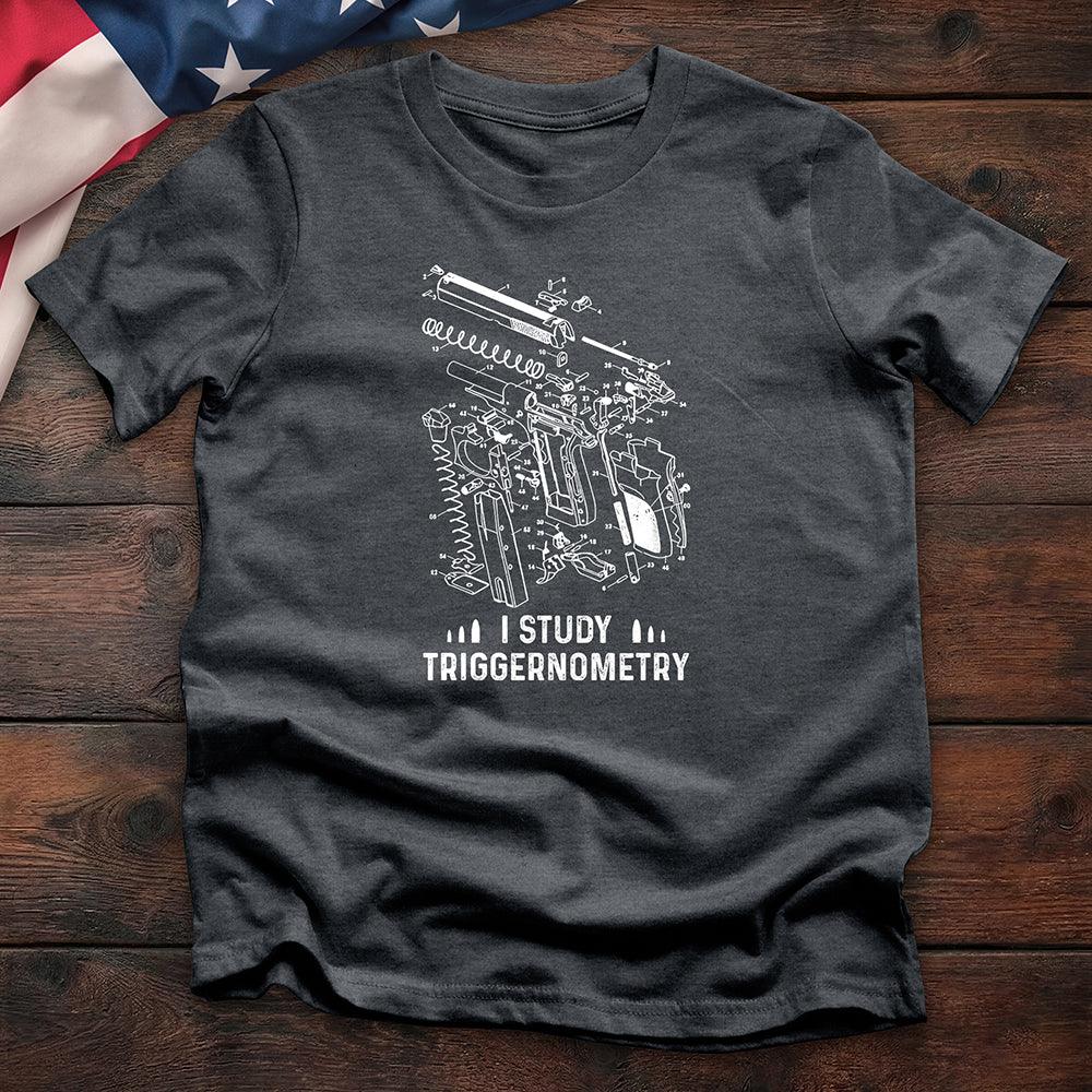 Dark heather t-shirt with gun schematic graphic and 'I Study Triggernometry' text on wooden surface