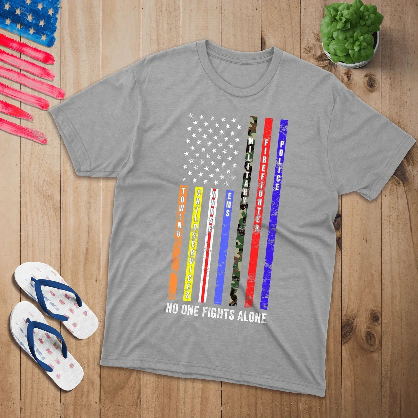 Gray Proud & Free tee on wood, US flag graphic with 'No One Fights Alone' for service heroes