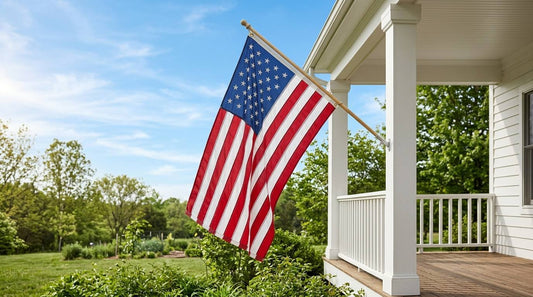 American flag flying from a porch pole beside a white house