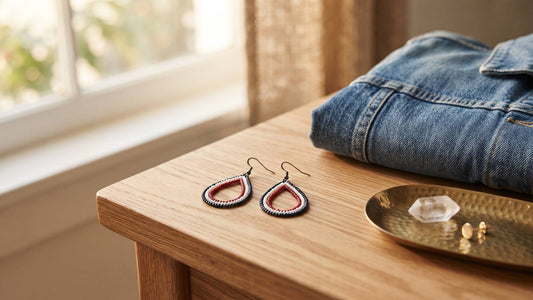 Flag-inspired teardrop earrings on a wood table beside folded denim and a brass tray