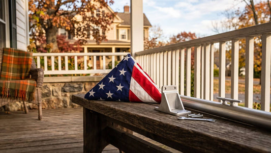 Folded American flag beside a wall bracket and flagpole on an autumn porch