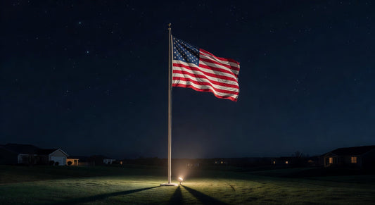 American flag waving on a flagpole at night, illuminated on a suburban lawn with starry sky