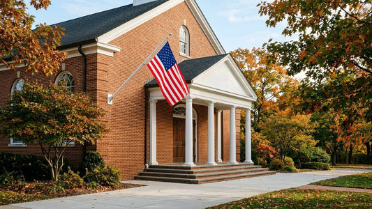 American flag displayed on a wall bracket outside a brick church in autumn