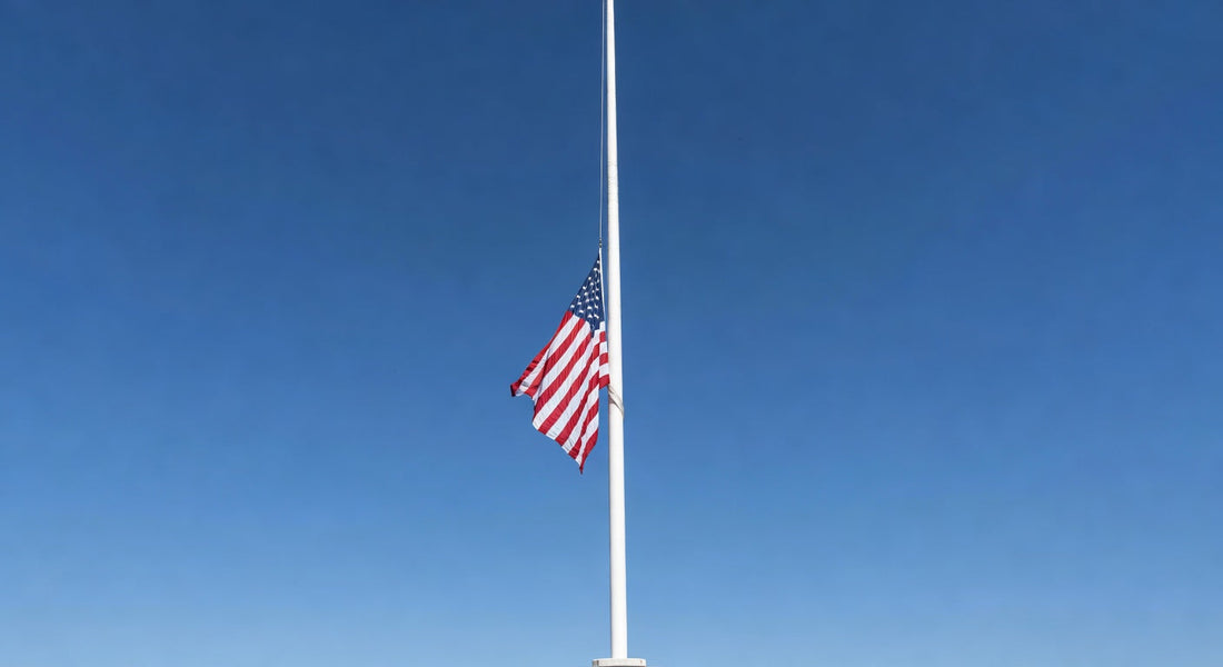 American flag at half-staff on flagpole against clear blue sky