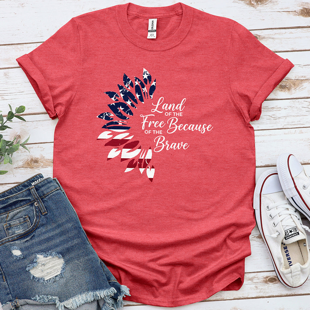 Heather red patriotic t-shirt with feather design and 'Land of the Free Because of the Brave' text, styled with denim shorts and sneakers