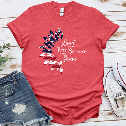 Heather red patriotic t-shirt with feather design and 'Land of the Free Because of the Brave' text, styled with denim shorts and sneakers