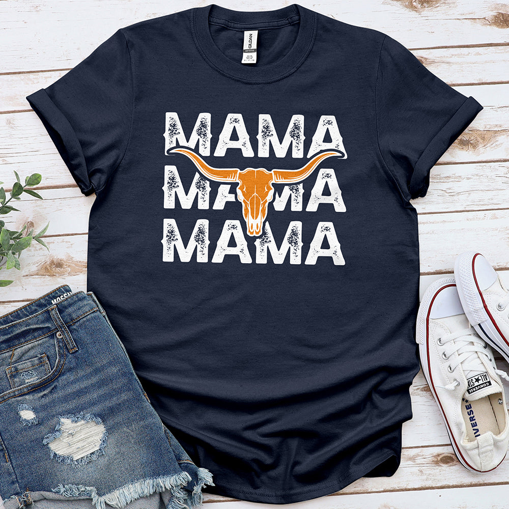 Navy blue graphic tee with distressed 'MAMA' text and longhorn skull, laid with denim shorts and sneakers