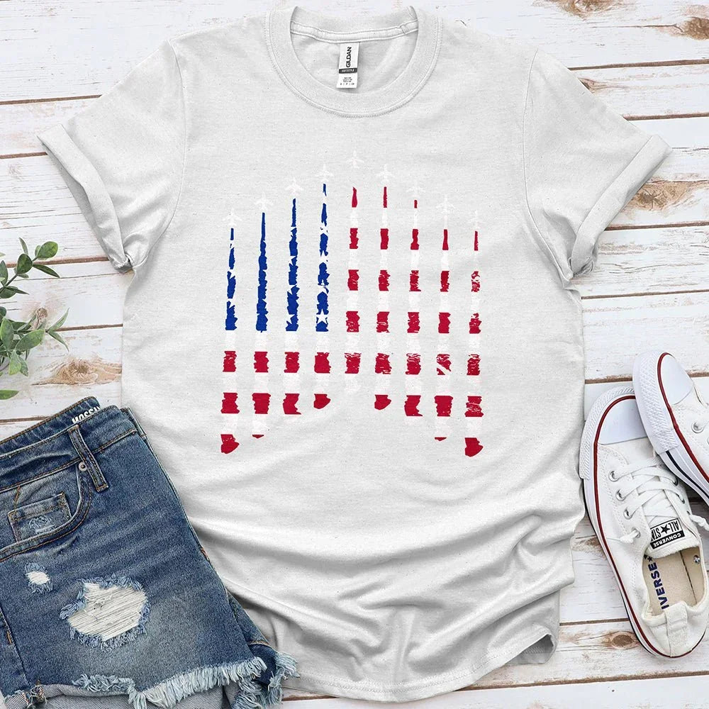 White Proud & Free tee with blue and red airplane flag graphic, laid with denim shorts and sneakers
