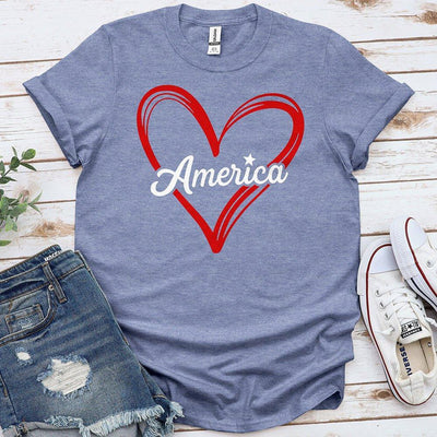 Blue Proud & Free t-shirt with red heart and America text, styled with denim shorts and sneakers