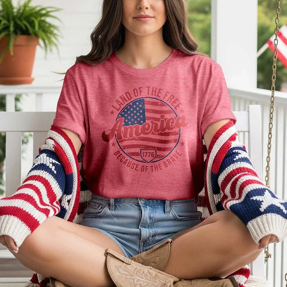 Woman on porch wearing red 'Land of the Free America' tee, patriotic cardigan, and denim shorts