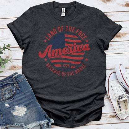 Black Proud & Free t-shirt with patriotic America flag design, paired with denim shorts and white sneakers.