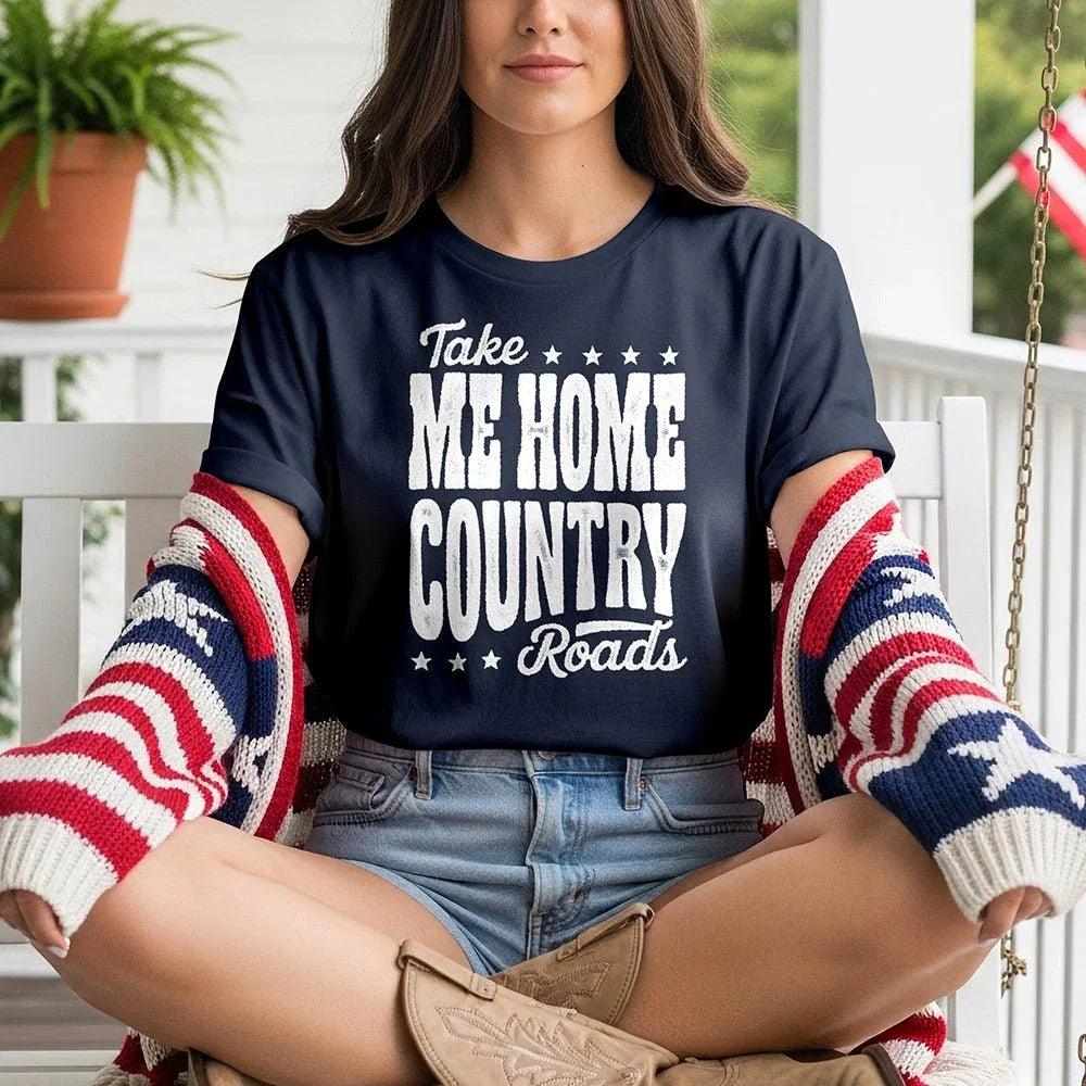 Woman in 'Take Me Home Country Roads' tee, denim shorts, and flag sweater on porch swing