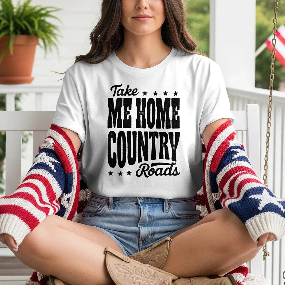 Woman on porch wearing 'Take Me Home Country Roads' tee, American flag sweater, denim shorts