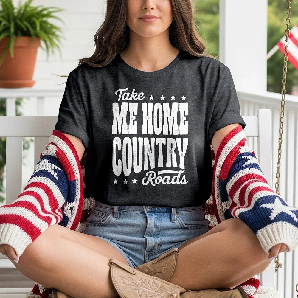 Woman on porch wearing 'Take Me Home Country Roads' t-shirt and American flag sweater