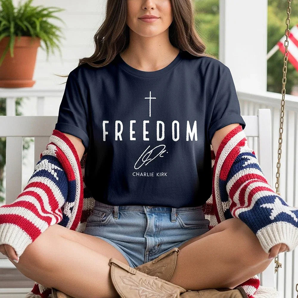 Woman in 'Freedom' Charlie Kirk tee and patriotic cardigan on porch swing, Proud & Free style.