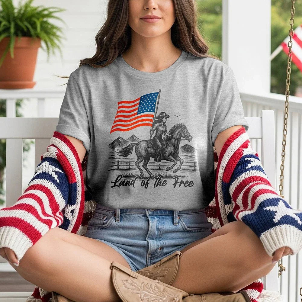 Woman wearing 'Land of the Free' patriotic t-shirt, flag sweater, sitting on porch