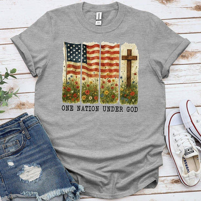 Gray t-shirt with American flag, cross, wildflowers, text 'One Nation Under God', flat lay