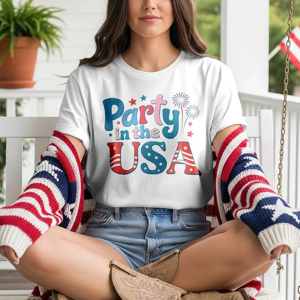 Woman in 'Party in the USA' graphic tee with patriotic cardigan and boots on porch