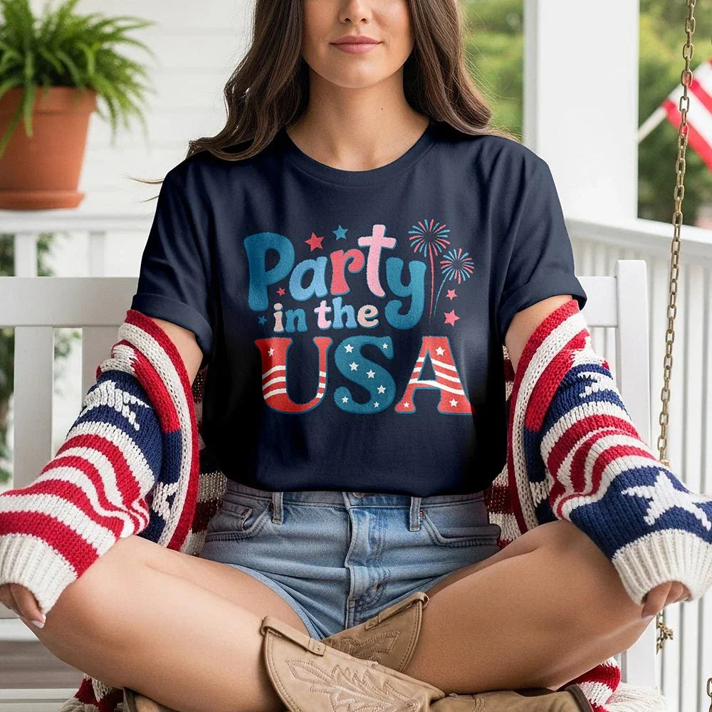 Woman in a 'Party in the USA' t-shirt, denim shorts, and flag sweater on porch swing