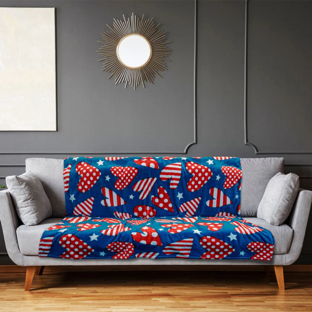 Patriotic hearts plush blanket with red, white, and blue heart patterns on a sofa in a modern living room.