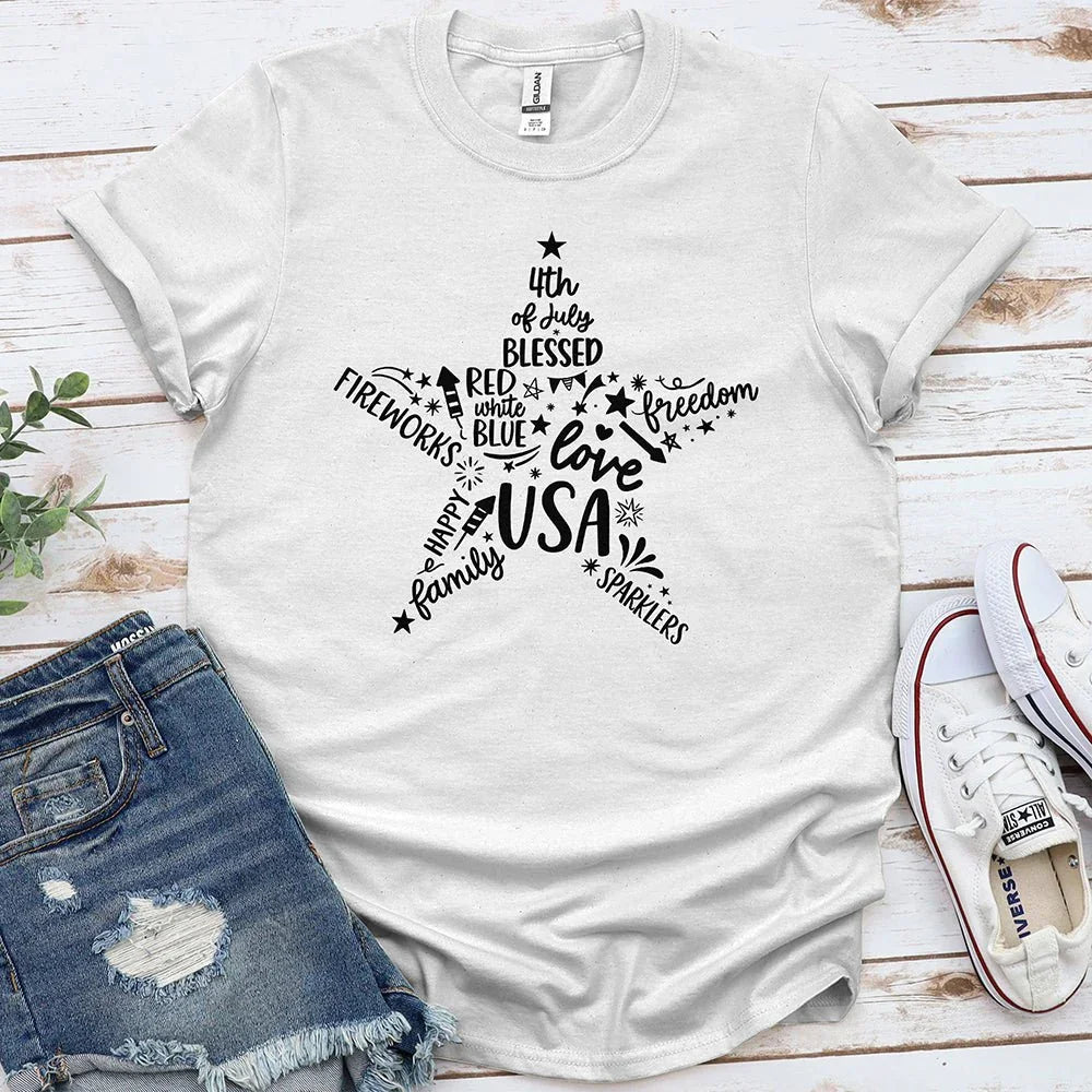 White Proud & Free Star of Freedom USA tee with patriotic text, laid beside denim shorts and sneakers.