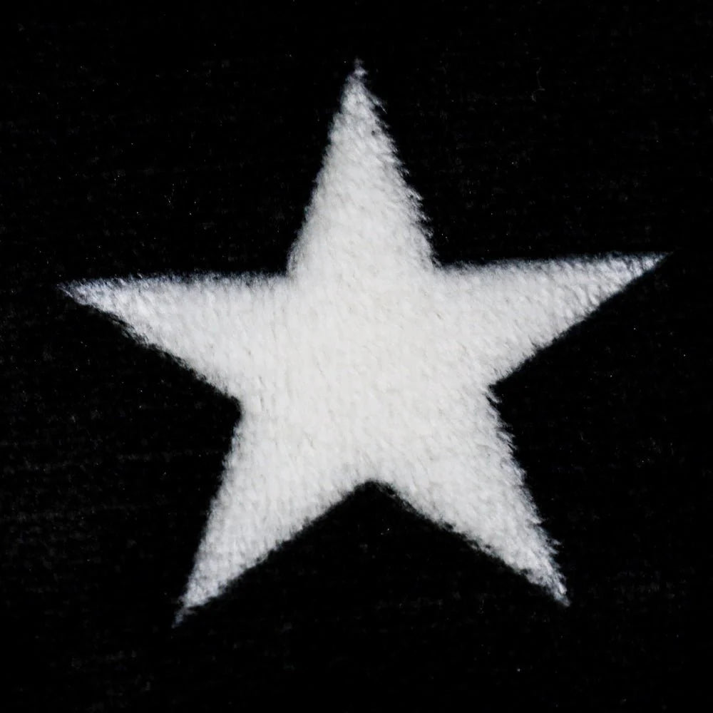 Close-up of soft plush blanket with white star on black background, Proud & Free decor