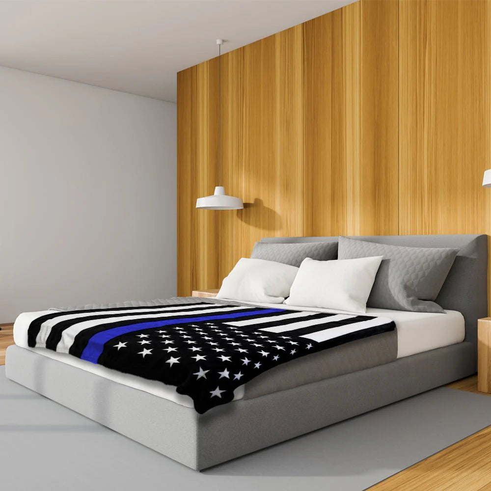 Thin blue line plush blanket with US flag design on modern bed, wooden accent wall