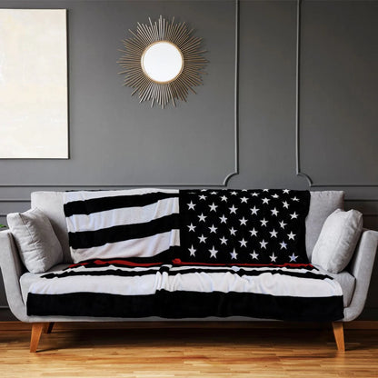 Thin red line American flag plush blanket on modern gray sofa in living room