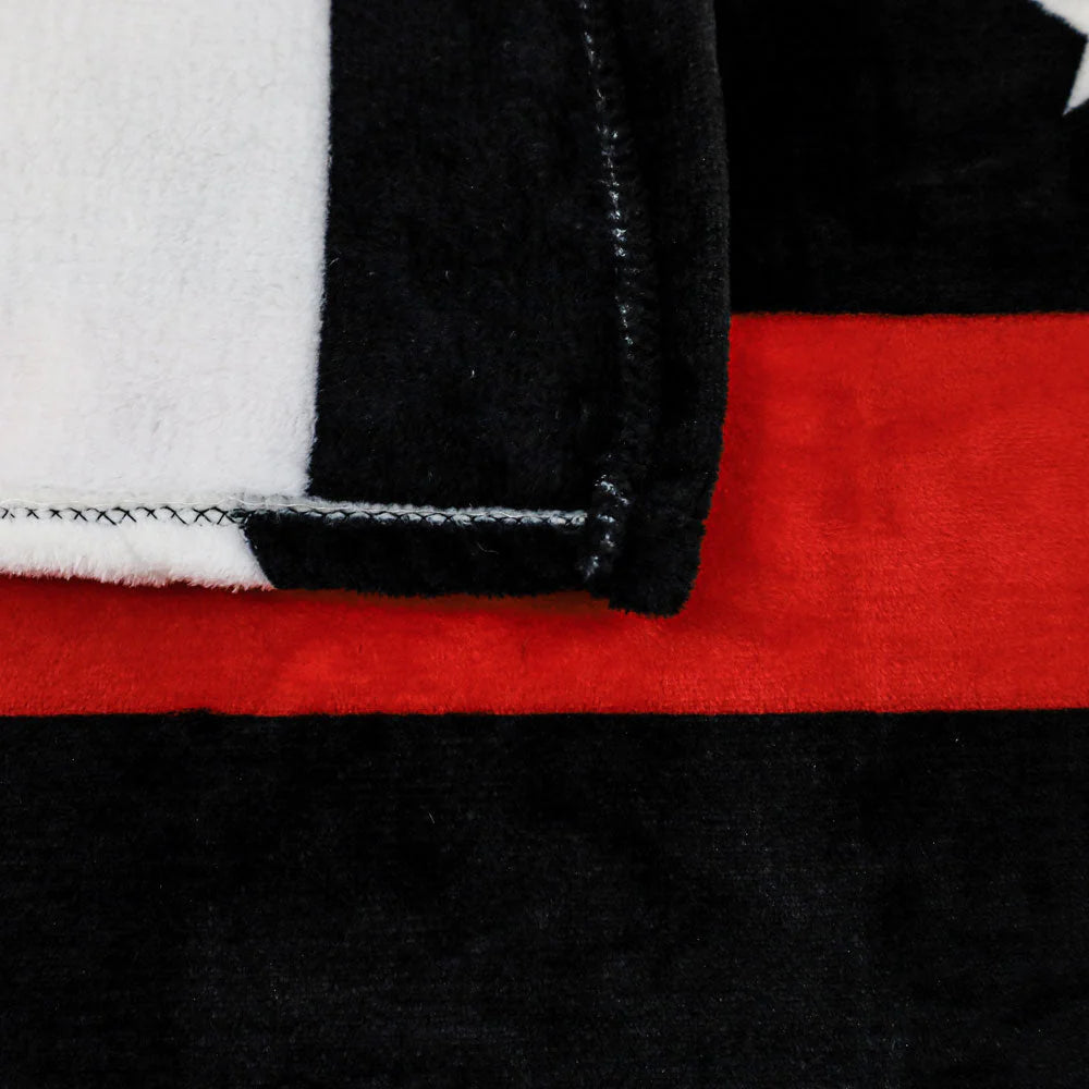 Soft plush blanket with thin red and black stripes and white accent, close-up texture