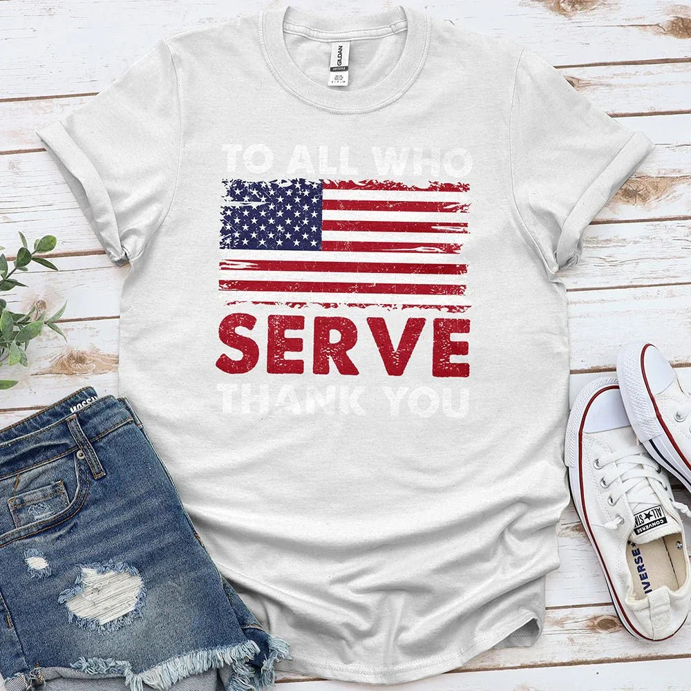 White t-shirt with American flag and 'To All Who Serve' text, styled with denim shorts and sneakers
