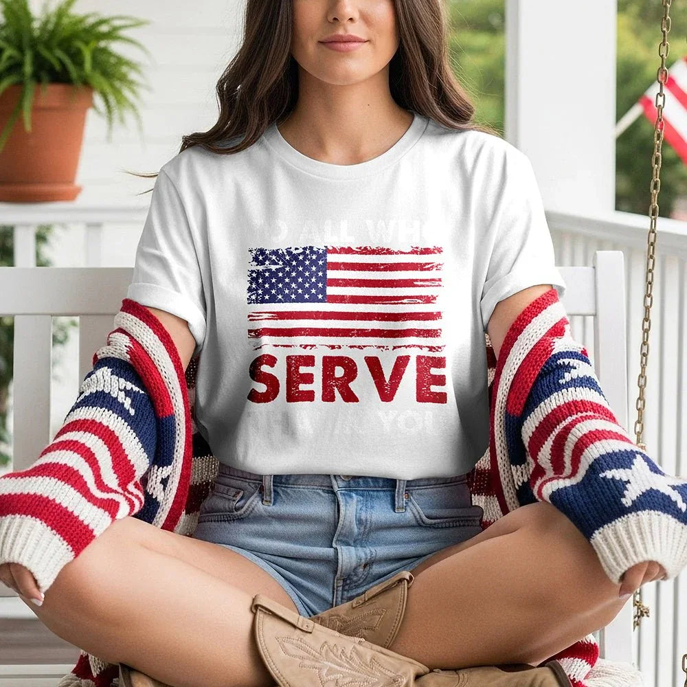 Woman wearing a 'To All Who Serve' patriotic tee with American flag, sitting on porch swing.