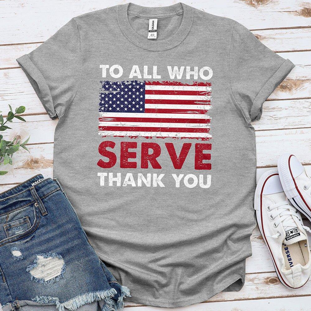 Gray Proud & Free patriotic tee with American flag and 'To All Who Serve Thank You' text, laid out with denim shorts and sneakers.